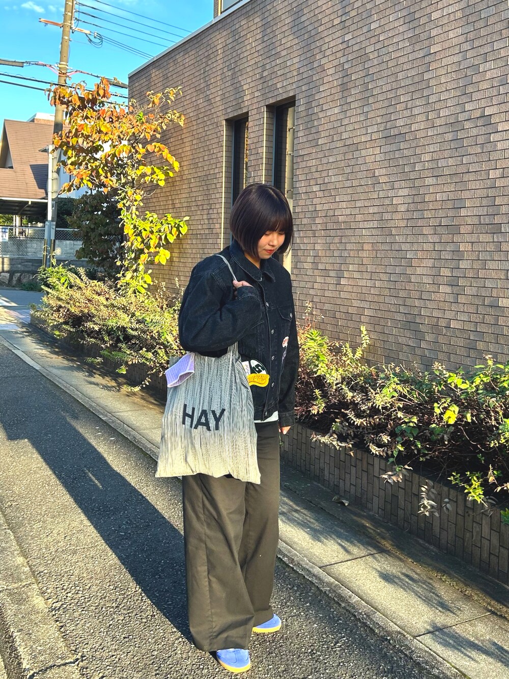 ブラック系のデニムジャケット、ブラック系のパンツ、グレー系のトートバッグを着用したレディースの秋コーディネートの2枚目の写真