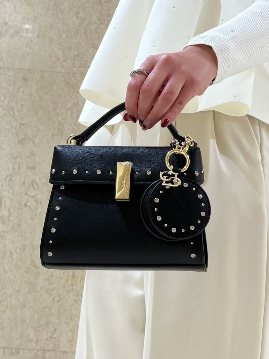 ブラック系のショルダーバッグ、ホワイト系のニット/セーター、ブラック系のキーケース/キーアクセサリーを着用したレディースの秋コーディネートの5枚目の写真