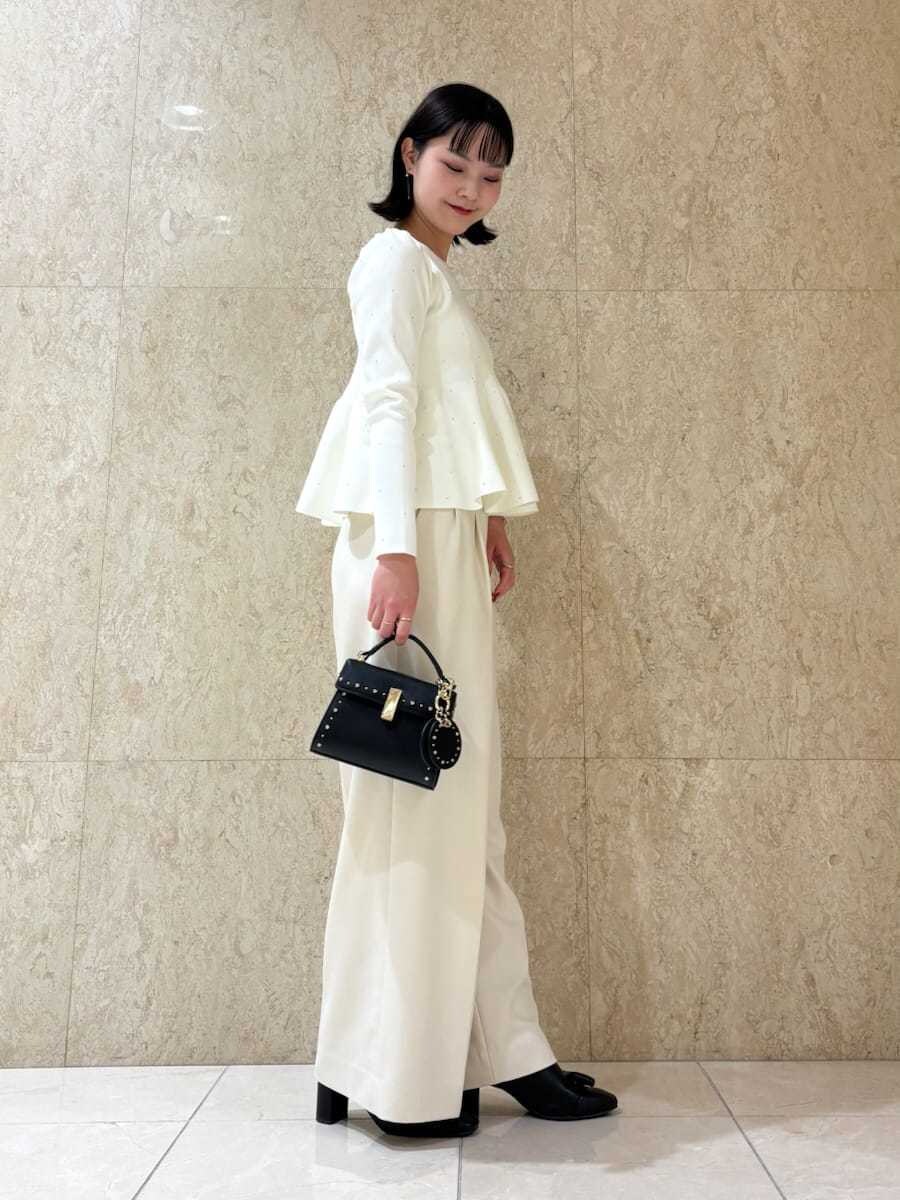 ブラック系のショルダーバッグ、ホワイト系のニット/セーター、ブラック系のキーケース/キーアクセサリーを着用したレディースの秋コーディネートの2枚目の写真