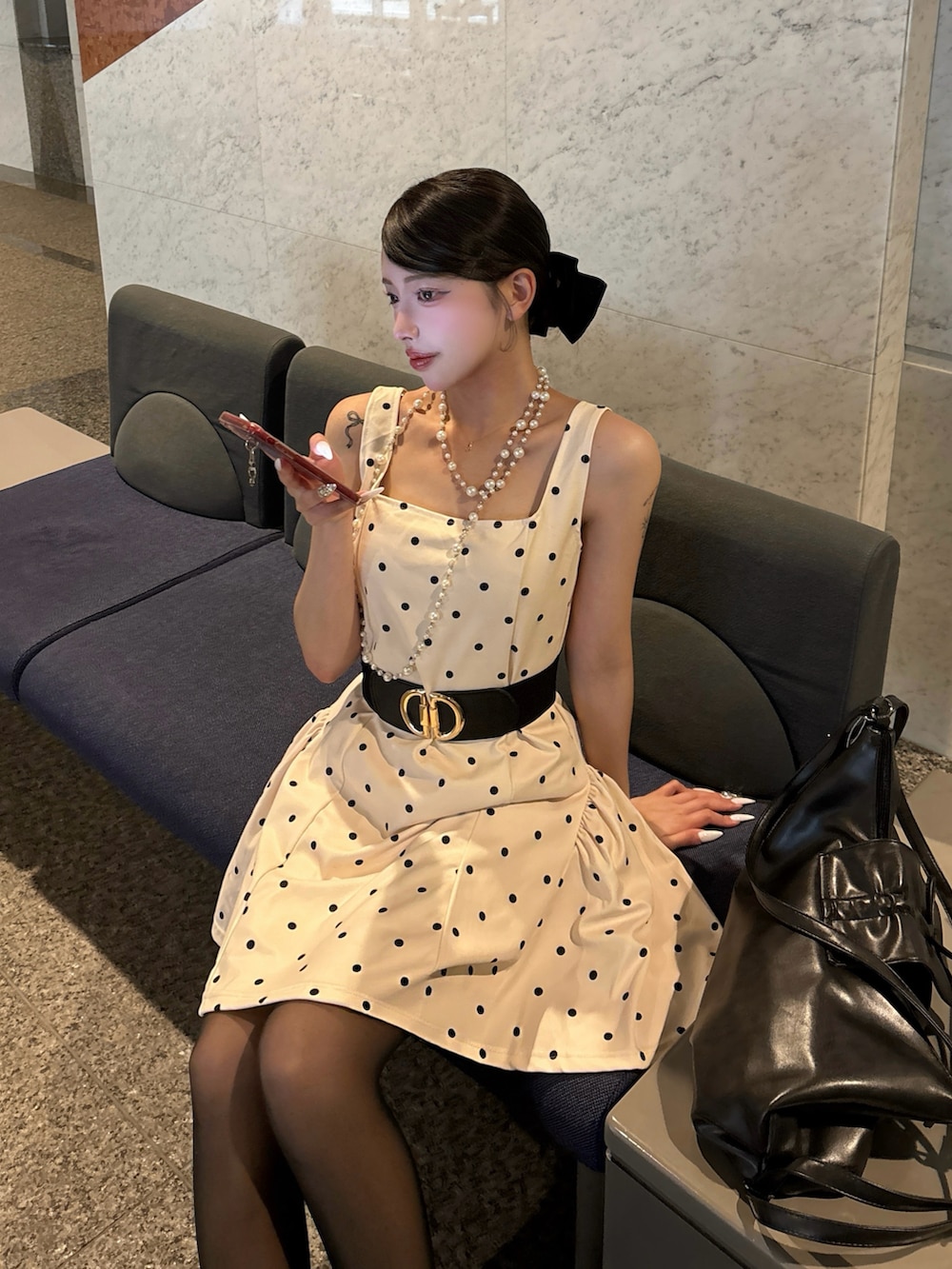 ホワイト系のワンピース、ブラック系のショルダーバッグを着用したレディースの春コーディネートの3枚目の写真