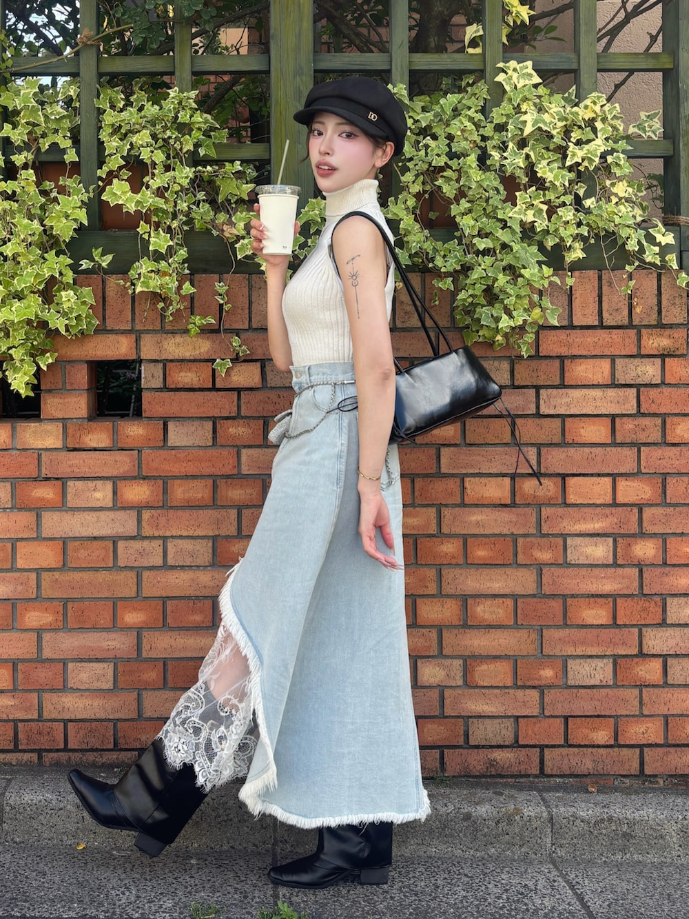 ブラック系のブーツ、ブルー系のデニムスカート、ブラック系のボストンバッグを着用したレディースの夏コーディネートの3枚目の写真