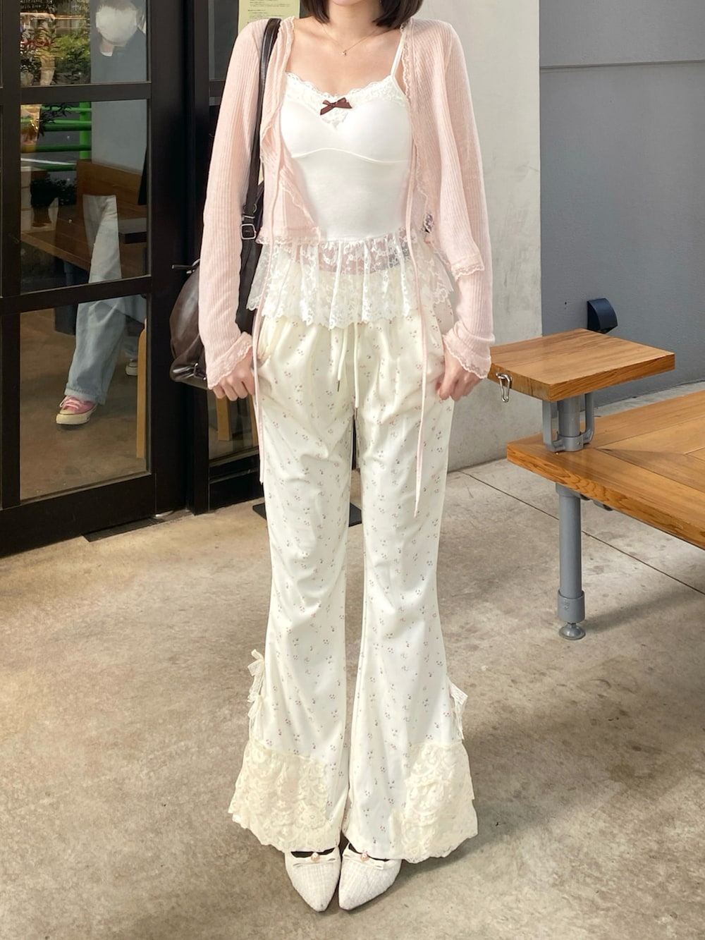 ブラウン系のショルダーバッグ、ホワイト系のキャミソール、ホワイト系のスウェットパンツを着用したレディースの冬コーディネートの3枚目の写真