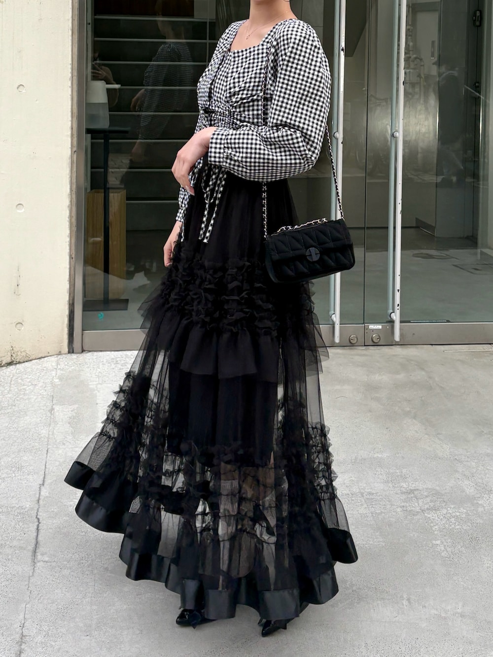 ブラック系のシャツ/ブラウス、ブラック系のスカート、ブラック系のショルダーバッグを着用したレディースの春コーディネートの3枚目の写真