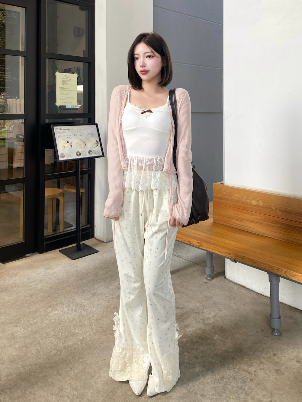 ブラウン系のショルダーバッグ、ホワイト系のキャミソール、ホワイト系のスウェットパンツを着用したレディースの冬コーディネートの2枚目の写真