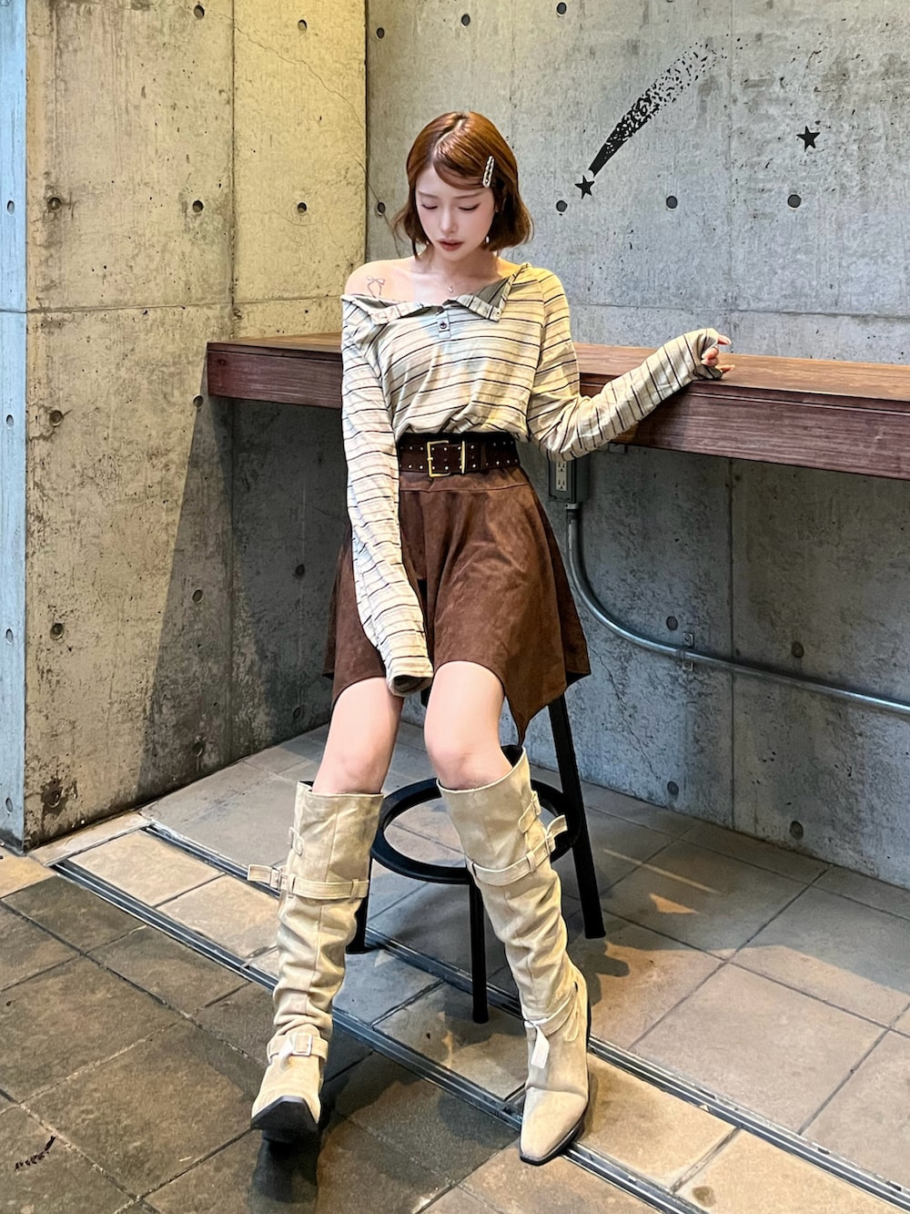 ブラウン系のTシャツ/カットソー、ベージュ系のブーツ、ブラウン系のスカートを着用したレディースの秋コーディネートの2枚目の写真