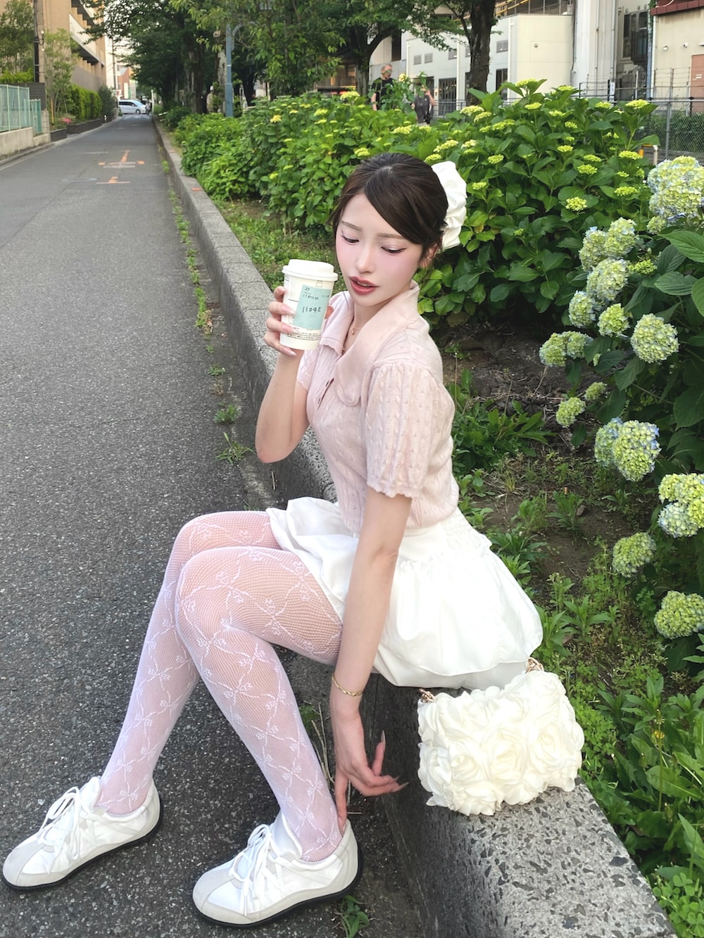 ピンク系のポロシャツ、ホワイト系のスカート、ホワイト系のタイツ/ストッキングを着用したレディースの夏コーディネートの2枚目の写真