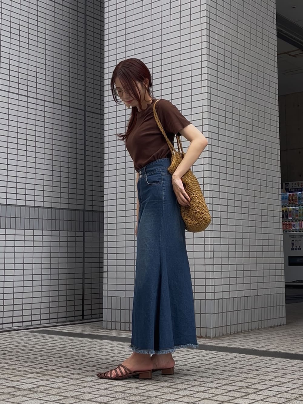 ブルー系のデニムスカート、ブラウン系のサンダル、ベージュ系のトートバッグを着用したレディースの夏コーディネートの3枚目の写真