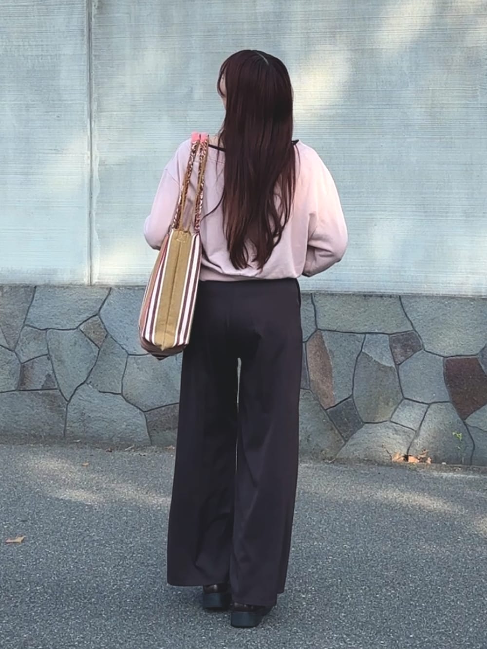 ピンク系のトートバッグ、ピンク系のスウェット、ブラウン系のスラックスを着用したレディースの春コーディネートの2枚目の写真