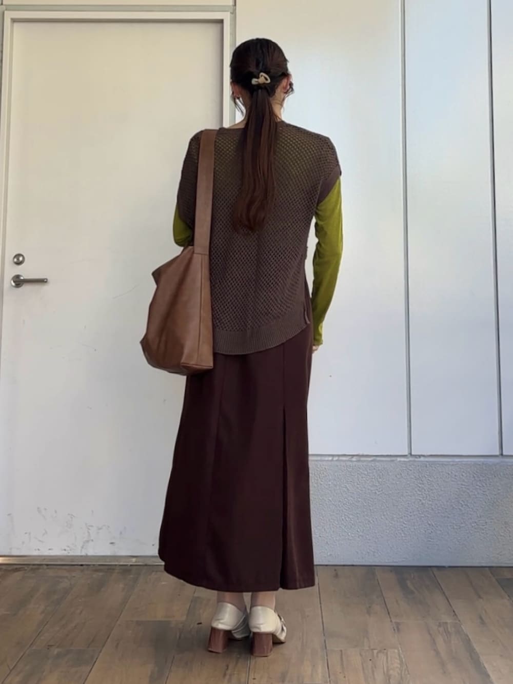 ブラウン系のスカート、ブラウン系のショルダーバッグ、グリーン系のTシャツ/カットソーを着用したレディースの秋コーディネートの2枚目の写真