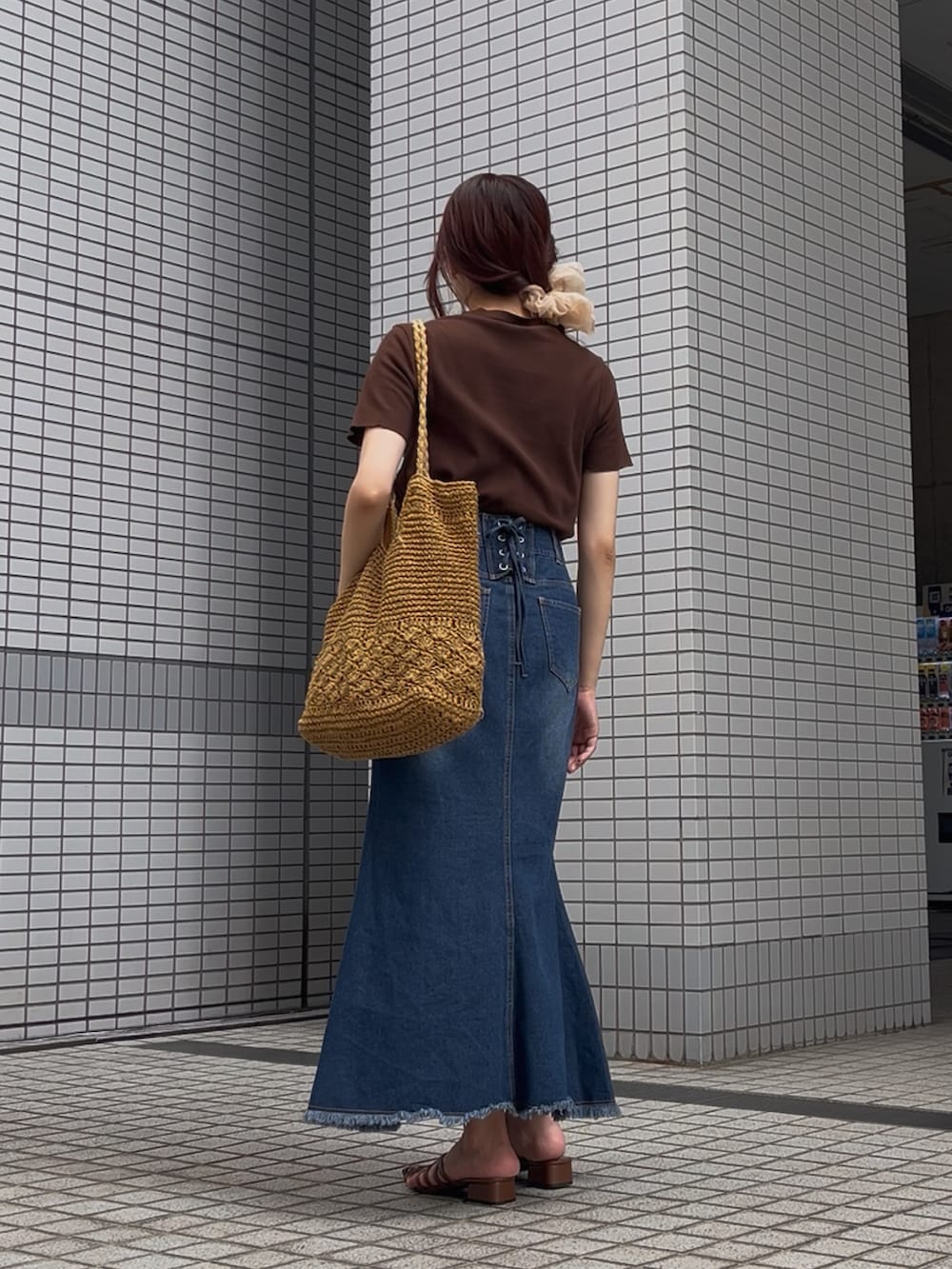 ブルー系のデニムスカート、ブラウン系のサンダル、ベージュ系のトートバッグを着用したレディースの夏コーディネートの2枚目の写真