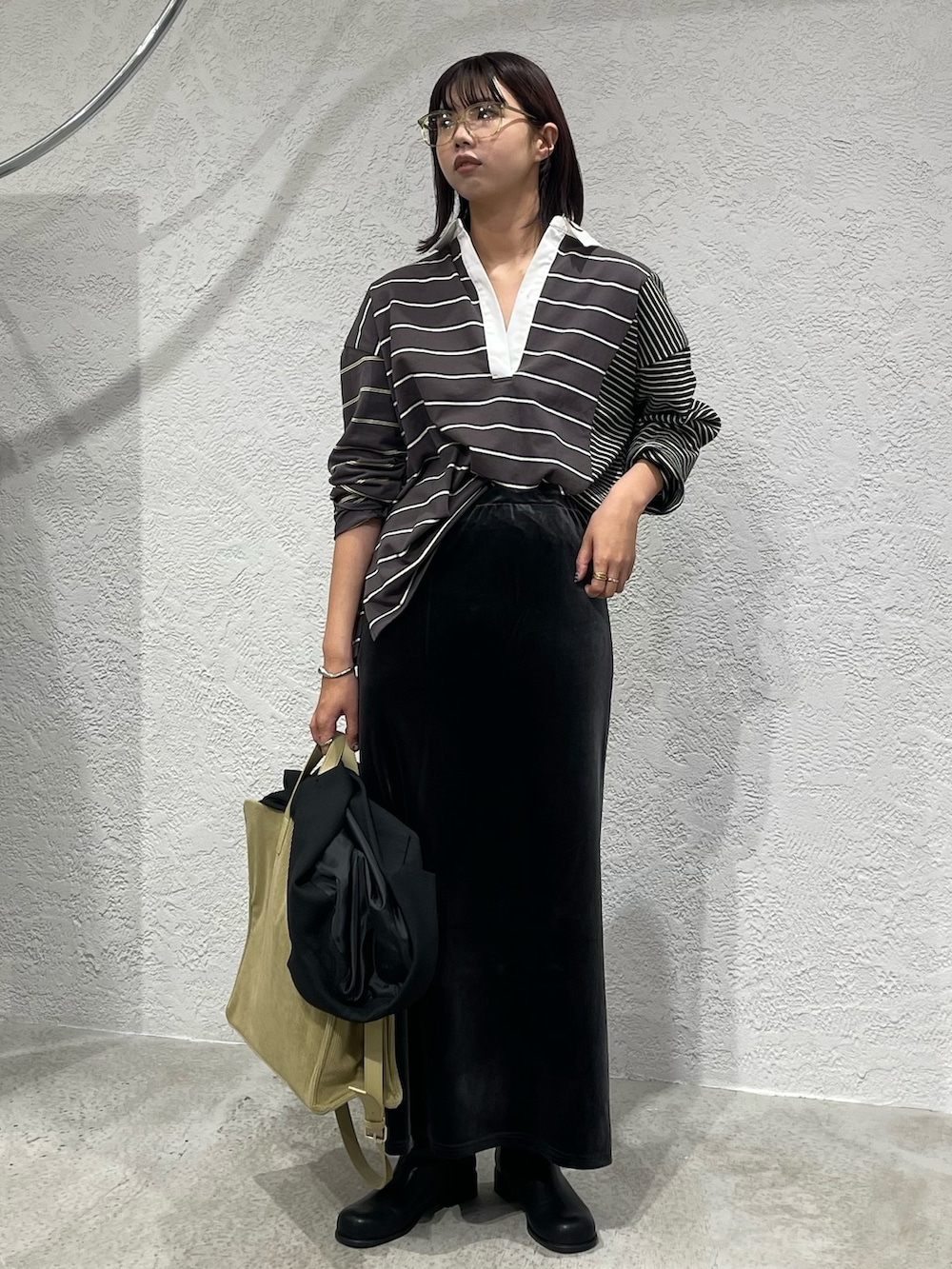 グレー系のスカート、ブラック系のTシャツ/カットソー、ブラック系のブーツを着用したレディースの秋コーディネートの3枚目の写真