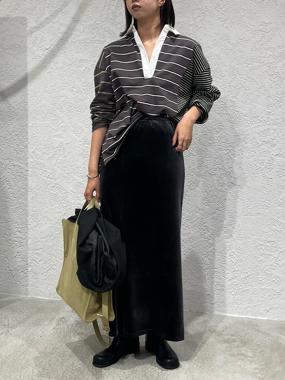 グレー系のスカート、ブラック系のTシャツ/カットソー、ブラック系のブーツを着用したレディースの秋コーディネートの2枚目の写真