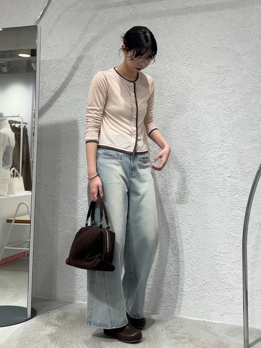 ブルー系のデニムパンツ、ブラウン系のボストンバッグ、ピンク系のカーディガン/ボレロを着用したレディースの春コーディネートの2枚目の写真