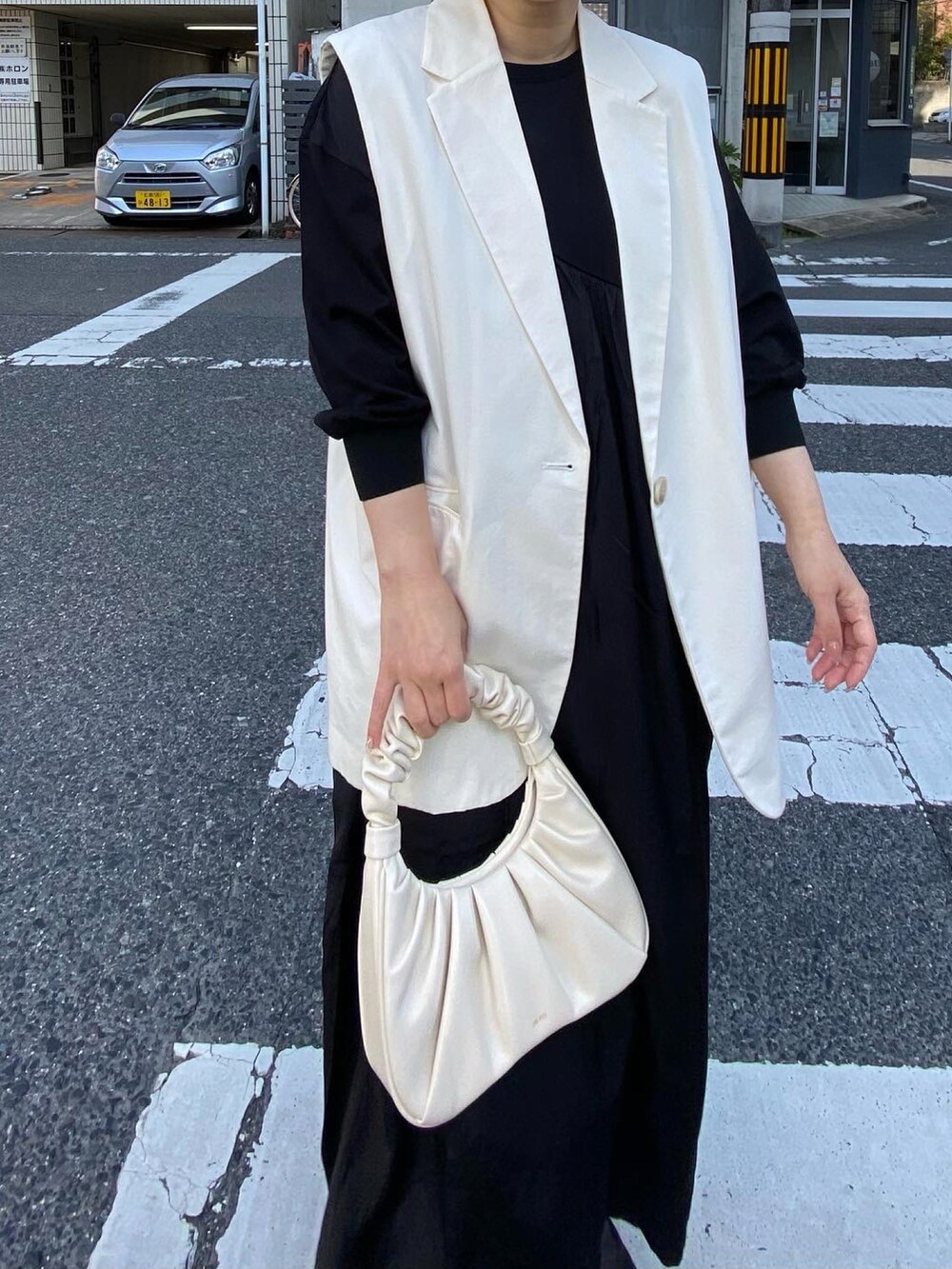 ブラック系のワンピース、ブラック系のブーツ、イエロー系のハットを着用したレディースの春コーディネートの4枚目の写真