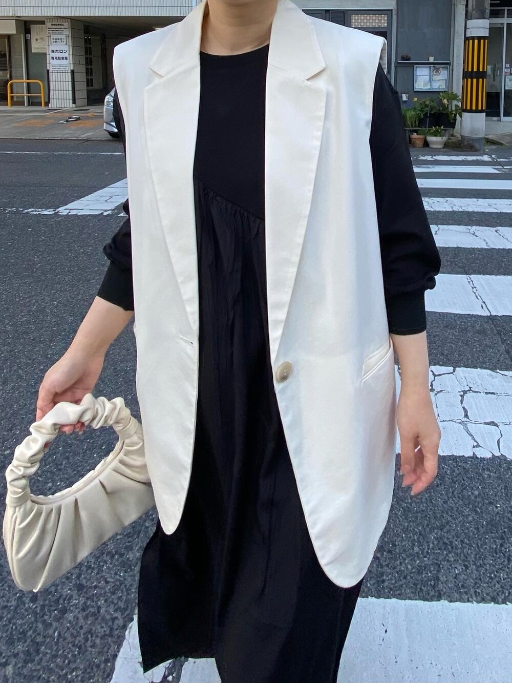 ブラック系のワンピース、ブラック系のブーツ、イエロー系のハットを着用したレディースの春コーディネートの2枚目の写真