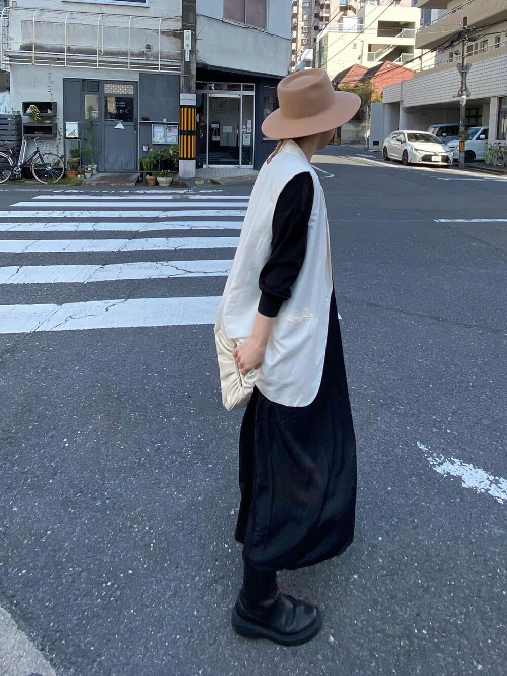 ブラック系のワンピース、ブラック系のブーツ、イエロー系のハットを着用したレディースの春コーディネートの3枚目の写真