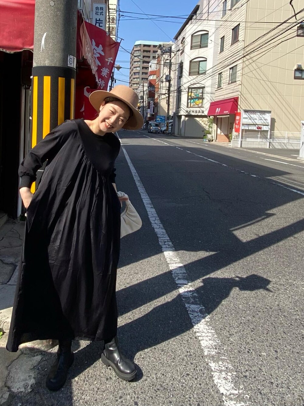 ブラック系のワンピース、ブラック系のブーツ、イエロー系のハットを着用したレディースの春コーディネートの5枚目の写真