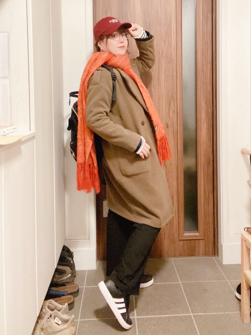 グリーン系のノーカラーコート、ブラック系のスラックス、ブルー系のカーディガン/ボレロを着用したレディースの秋コーディネートの2枚目の写真