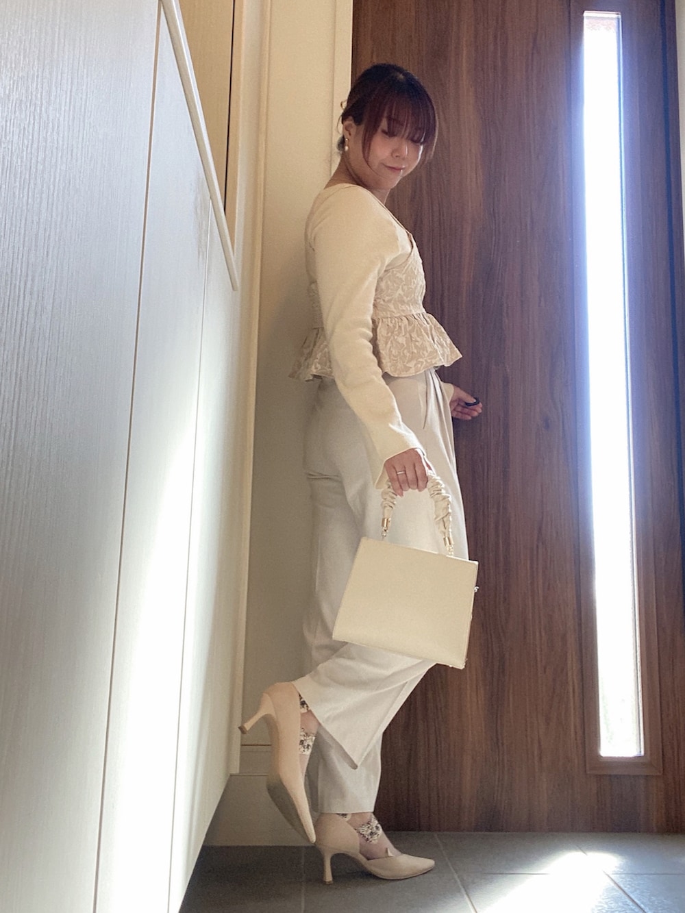 ベージュ系のハンドバッグ、ホワイト系のスラックス、ホワイト系のニット/セーターを着用したレディースの冬コーディネートの3枚目の写真