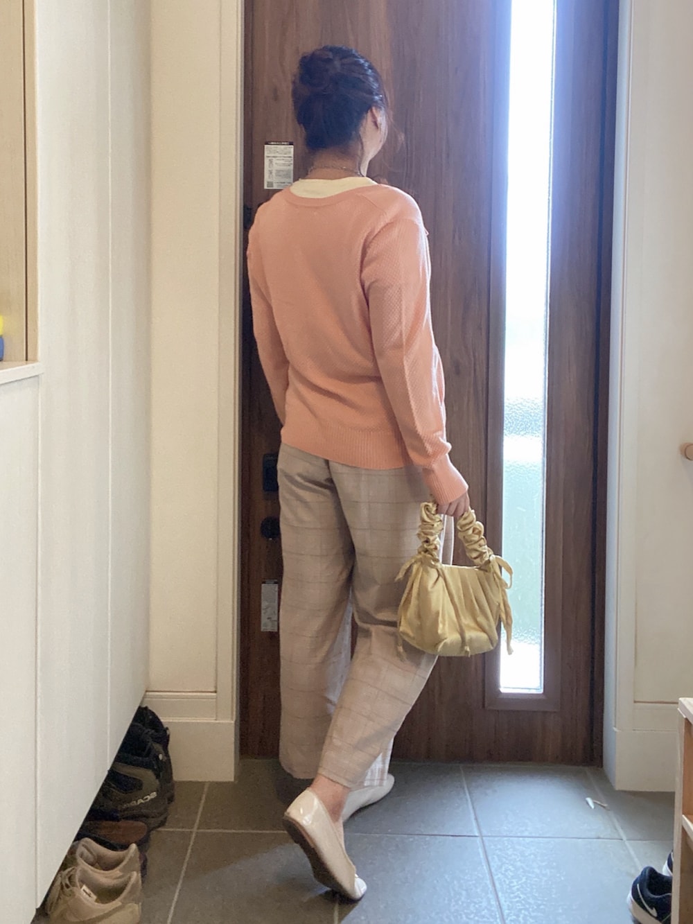 イエロー系のトートバッグ、ベージュ系のパンツ、ピンク系のカーディガン/ボレロを着用したレディースの秋コーディネートの3枚目の写真