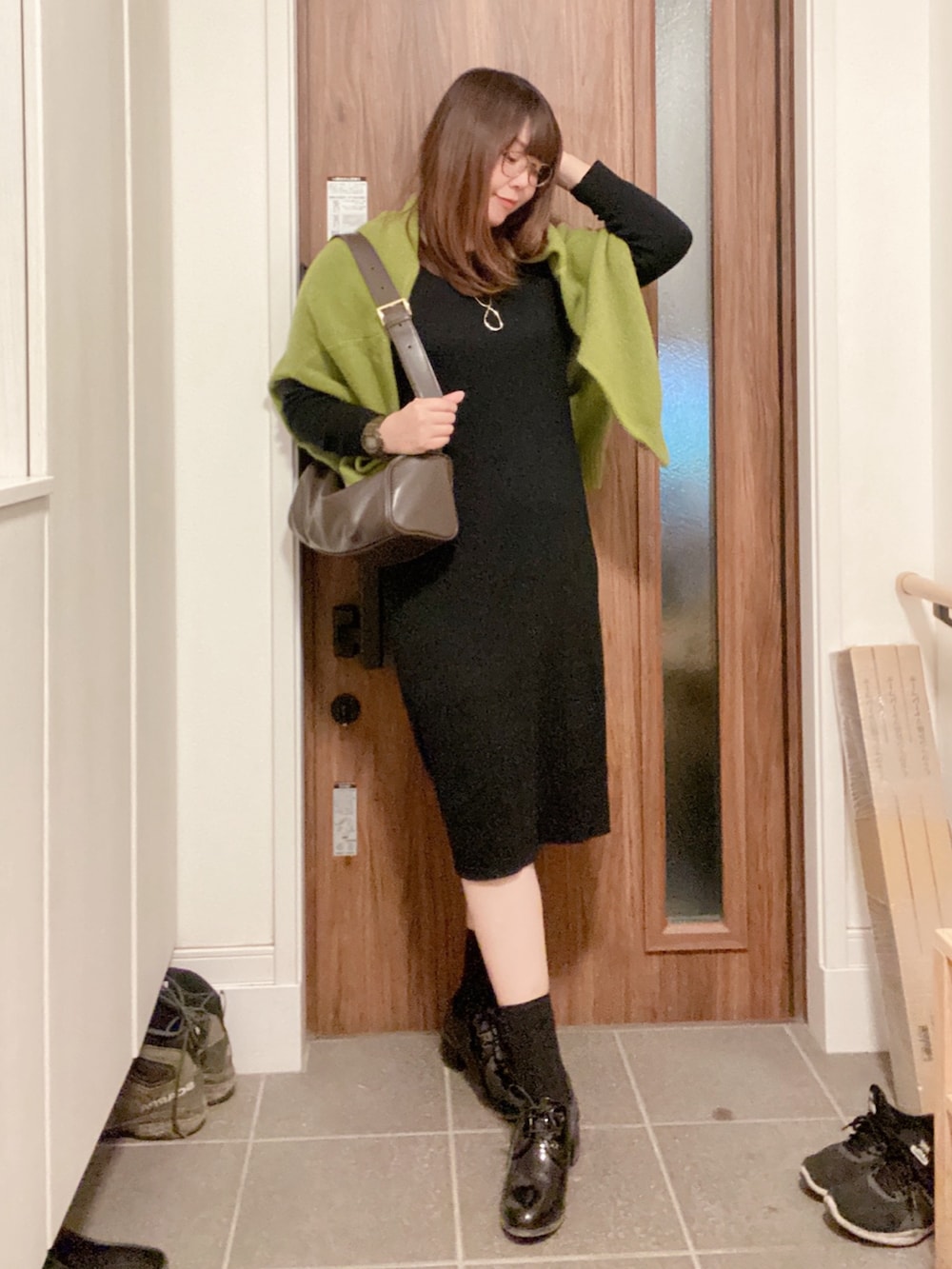 ブラック系のブーティ、ブラック系のワンピース、グリーン系のカーディガン/ボレロを着用したレディースの冬コーディネートの2枚目の写真