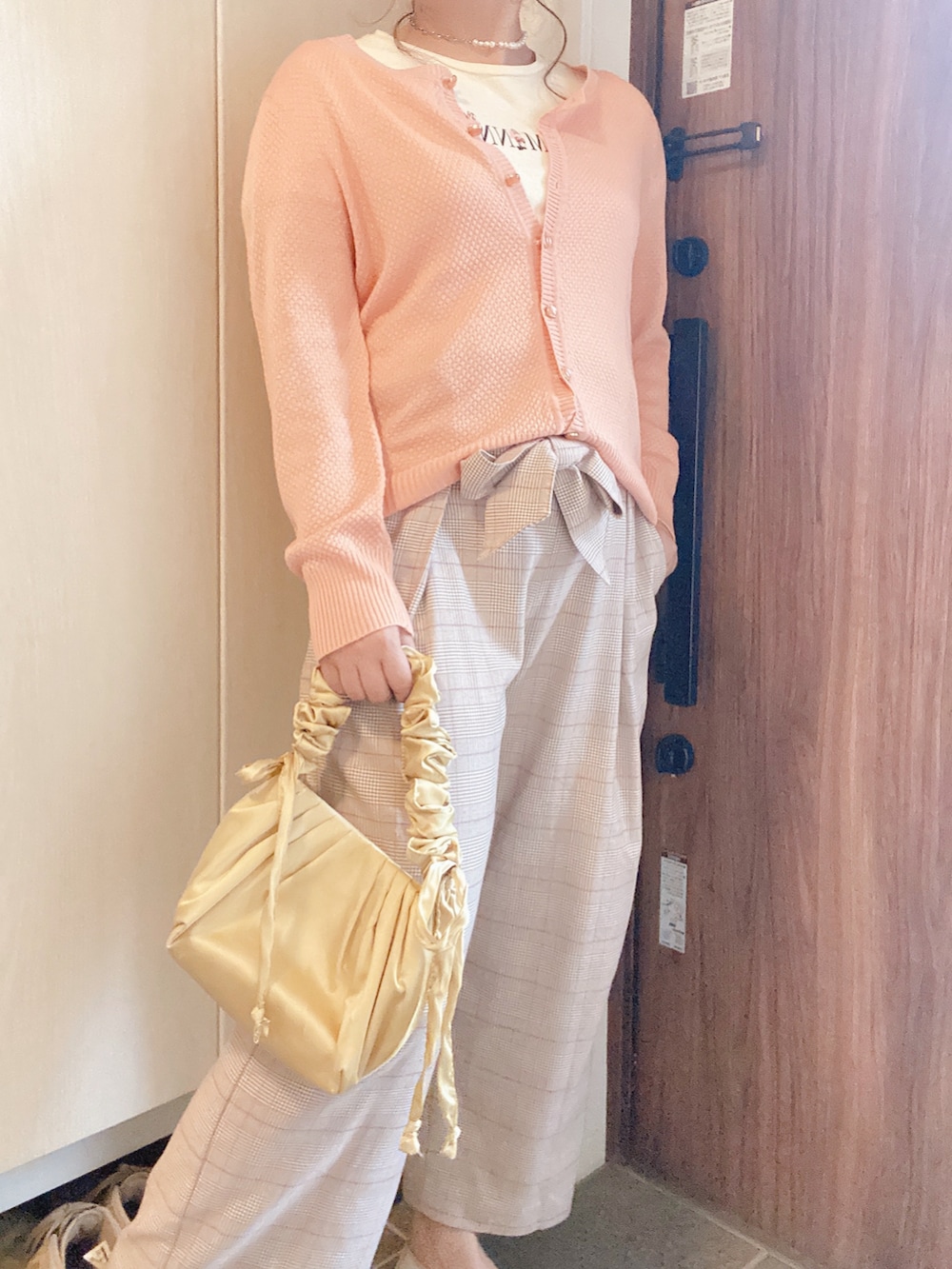 イエロー系のトートバッグ、ベージュ系のパンツ、ピンク系のカーディガン/ボレロを着用したレディースの秋コーディネートの4枚目の写真