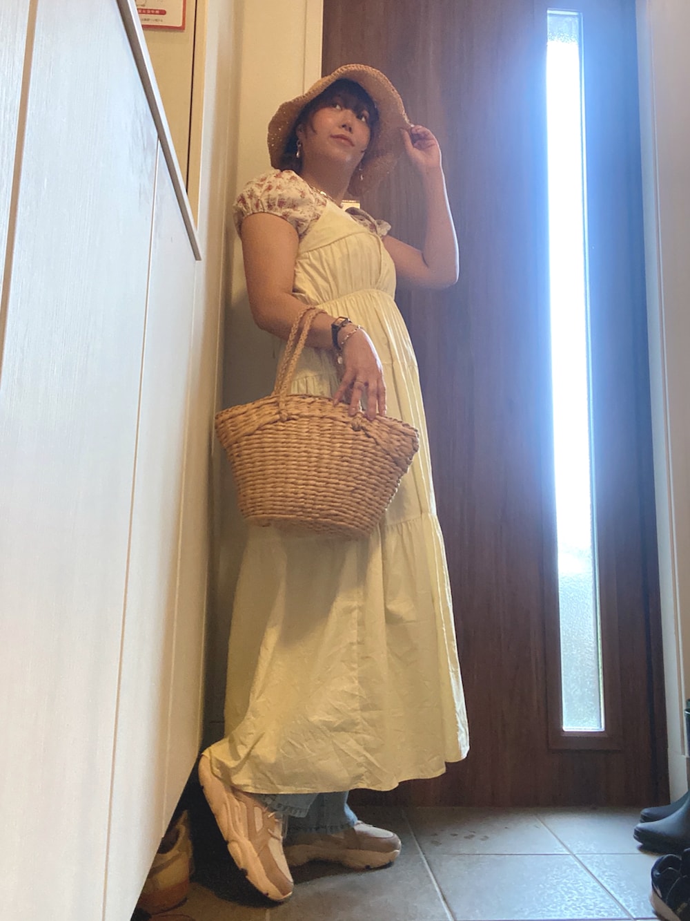 ピンク系のスニーカー、イエロー系のワンピース、ベージュ系のかごバッグを着用したレディースの夏コーディネートの2枚目の写真