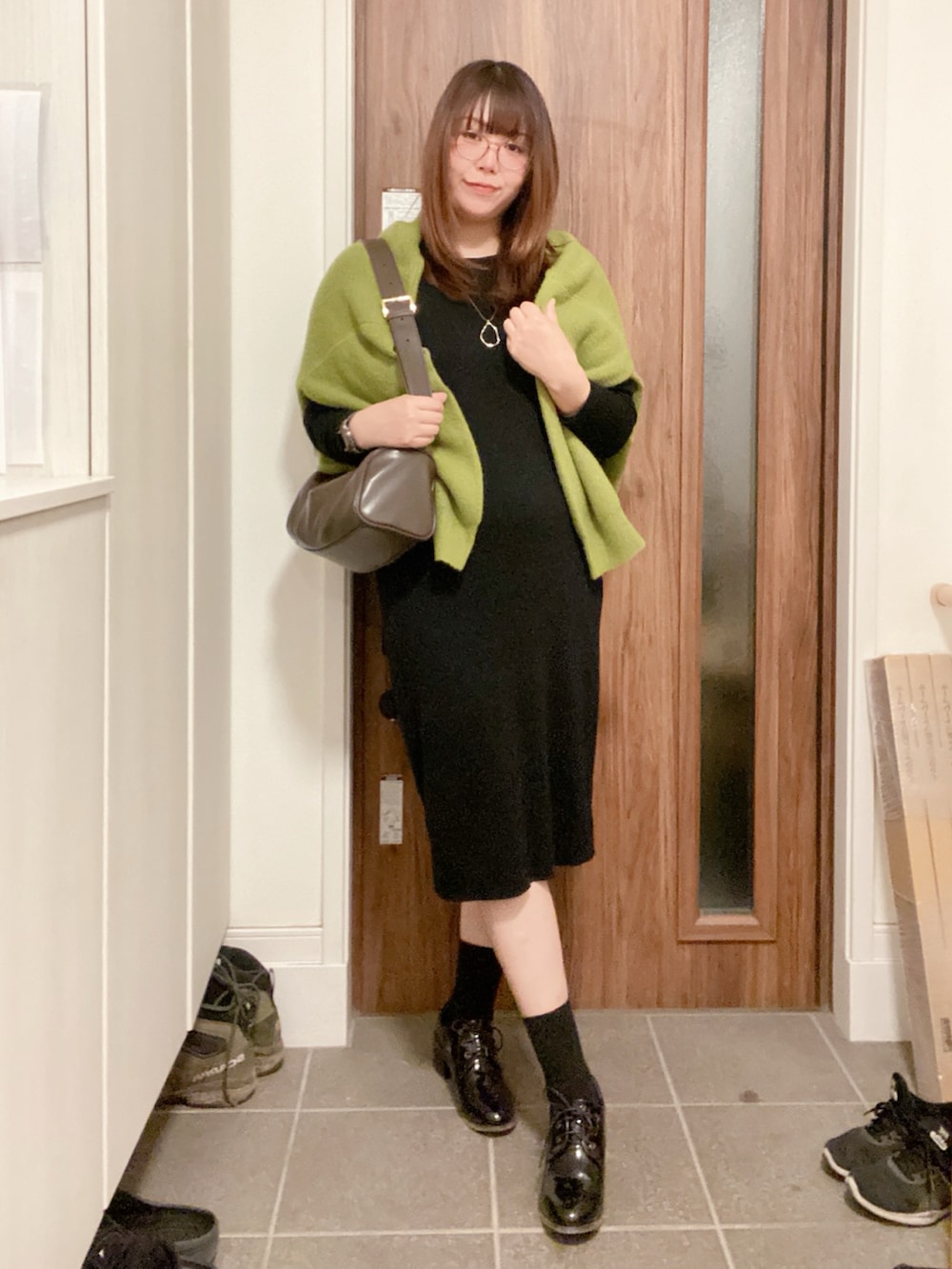 ブラック系のブーティ、ブラック系のワンピース、グリーン系のカーディガン/ボレロを着用したレディースの冬コーディネートの3枚目の写真