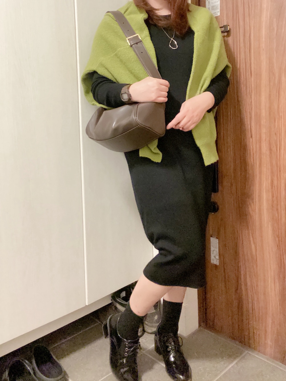 ブラック系のブーティ、ブラック系のワンピース、グリーン系のカーディガン/ボレロを着用したレディースの冬コーディネートの4枚目の写真
