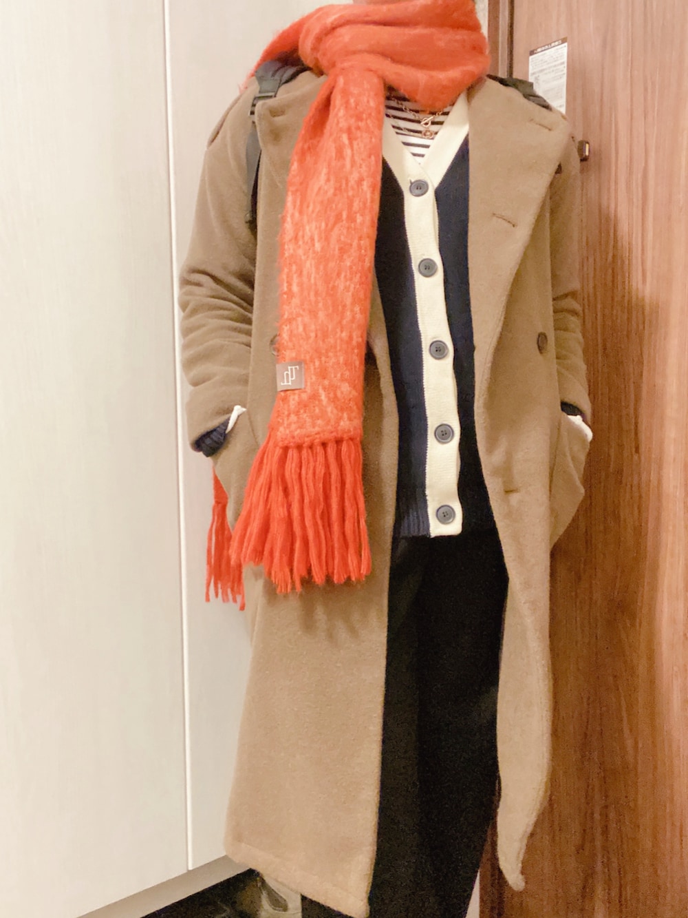 グリーン系のノーカラーコート、ブラック系のスラックス、ブルー系のカーディガン/ボレロを着用したレディースの秋コーディネートの4枚目の写真