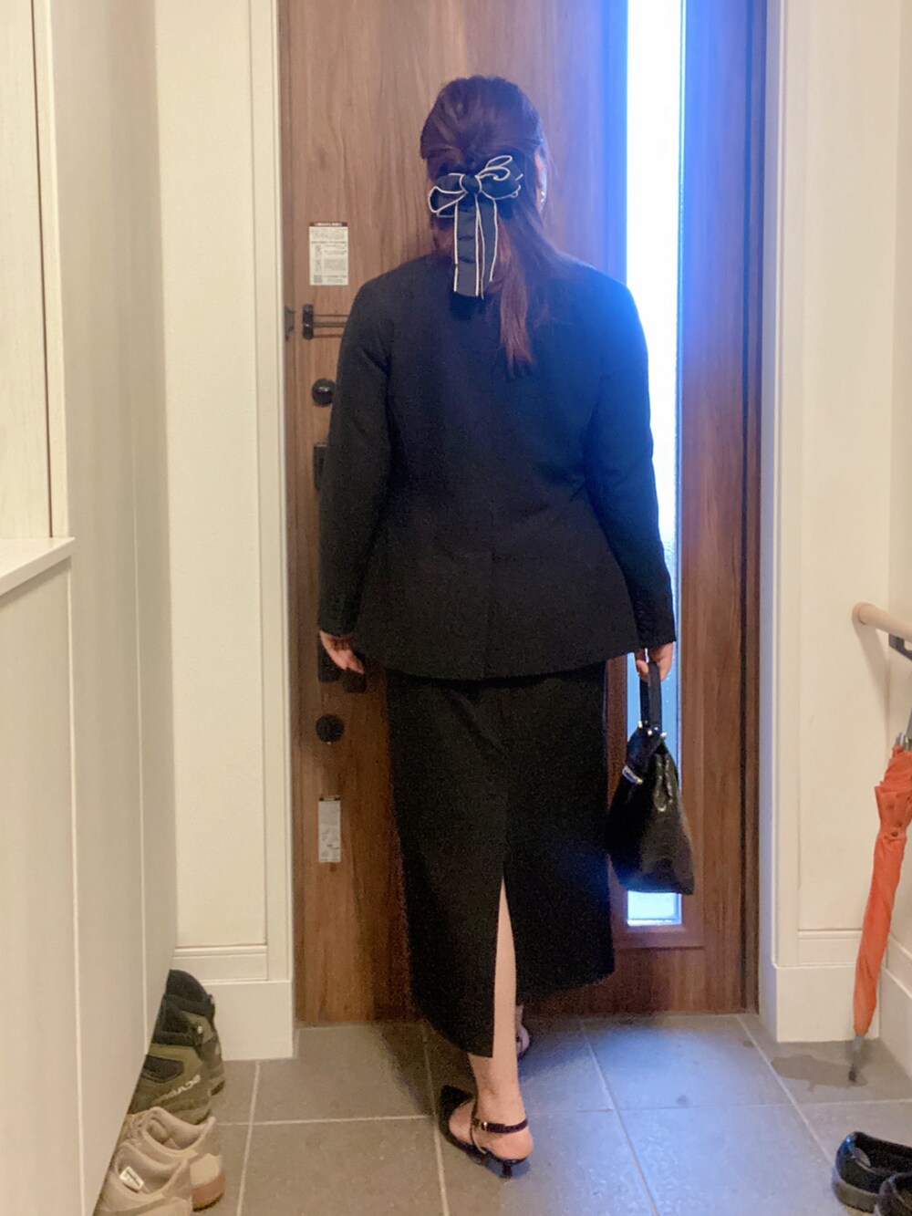 ブラック系のパンプス、ブラック系のハンドバッグ、ブルー系のキャミソールを着用したレディースの春コーディネートの2枚目の写真