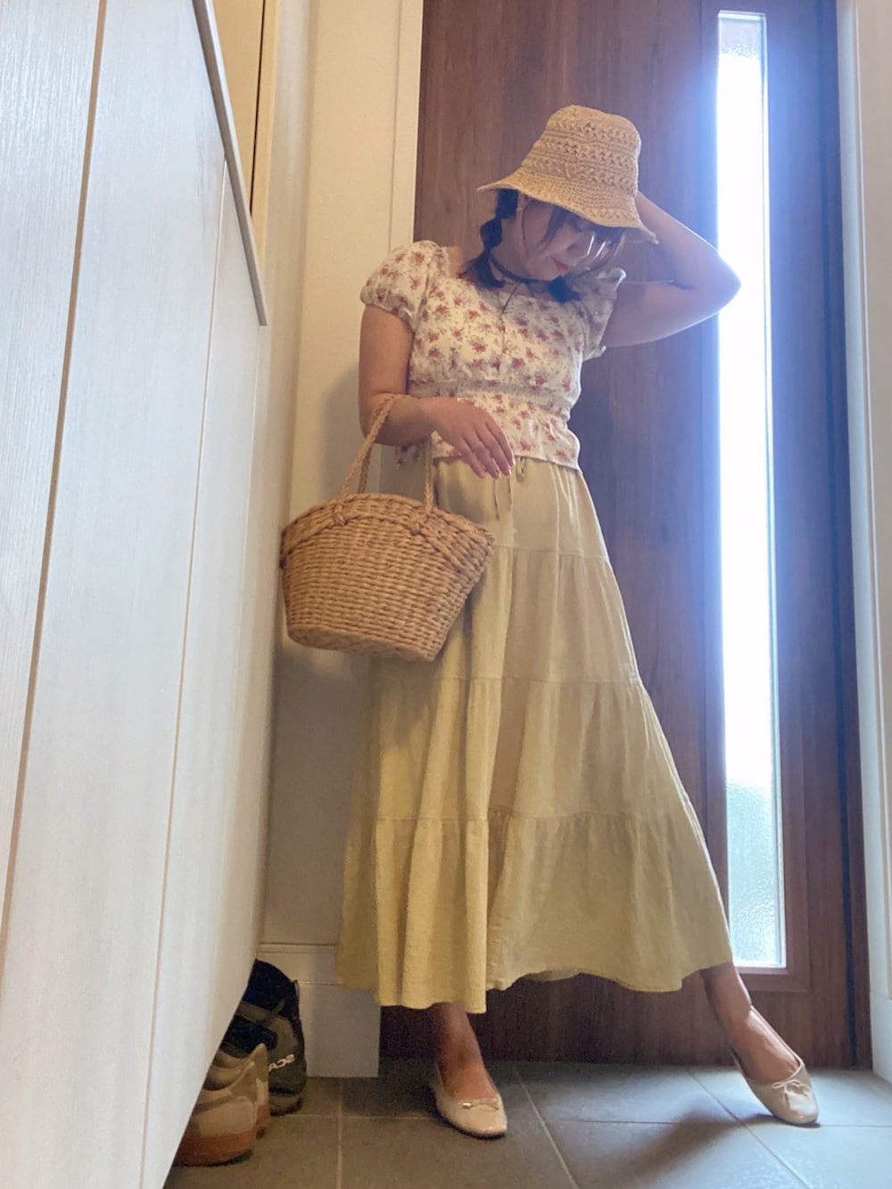 イエロー系のスカート、ベージュ系のかごバッグ、ホワイト系のバレエシューズを着用したレディースの春コーディネートの2枚目の写真