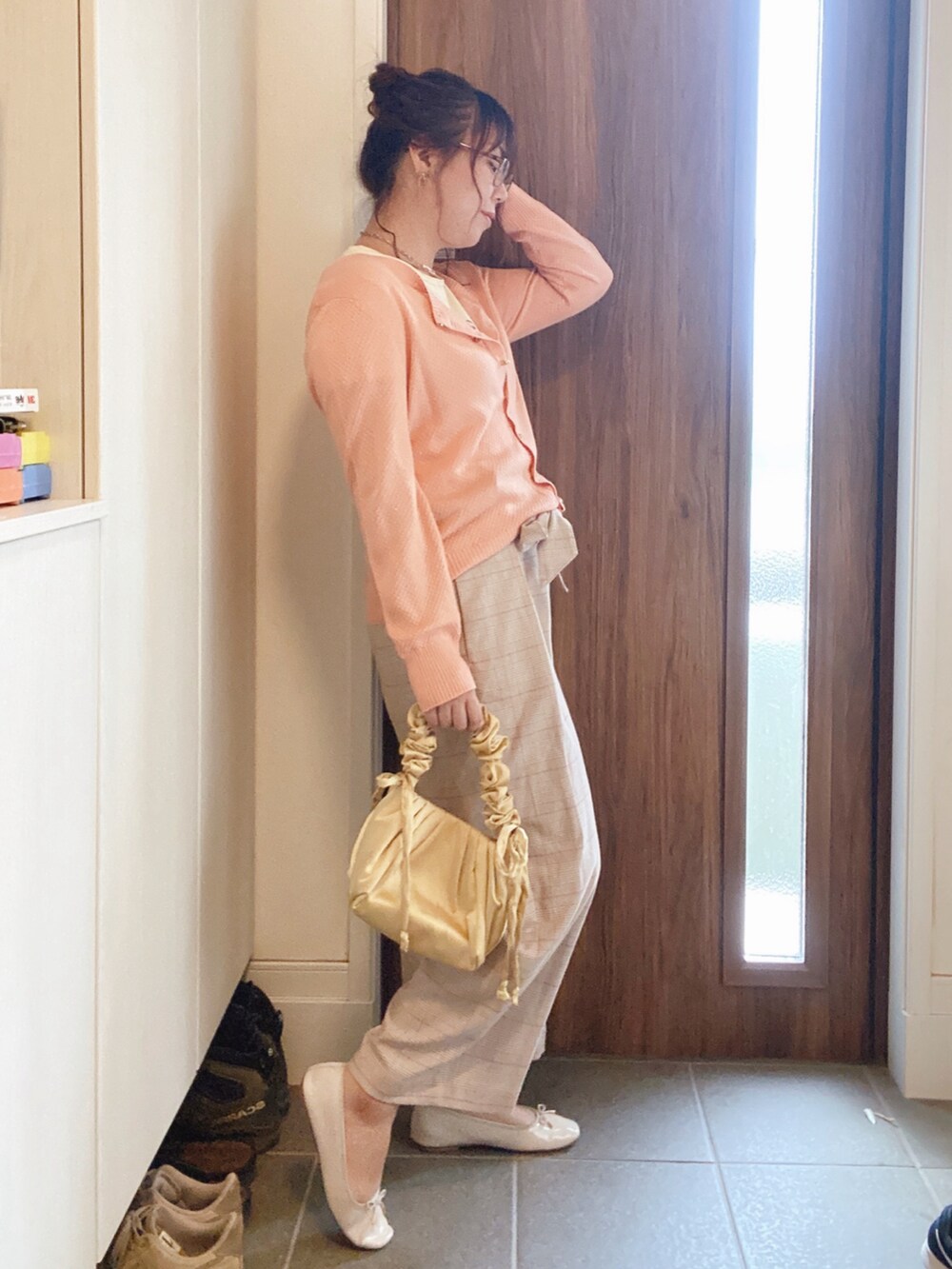 イエロー系のトートバッグ、ベージュ系のパンツ、ピンク系のカーディガン/ボレロを着用したレディースの秋コーディネートの2枚目の写真