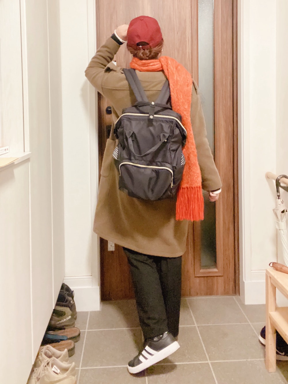 グリーン系のノーカラーコート、ブラック系のスラックス、ブルー系のカーディガン/ボレロを着用したレディースの秋コーディネートの3枚目の写真