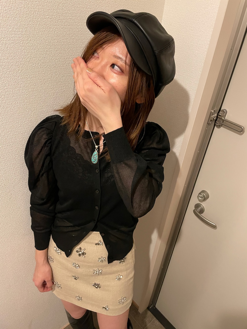 ベージュ系のスカート、ブラック系のアンサンブルを着用したレディースの冬コーディネートの2枚目の写真