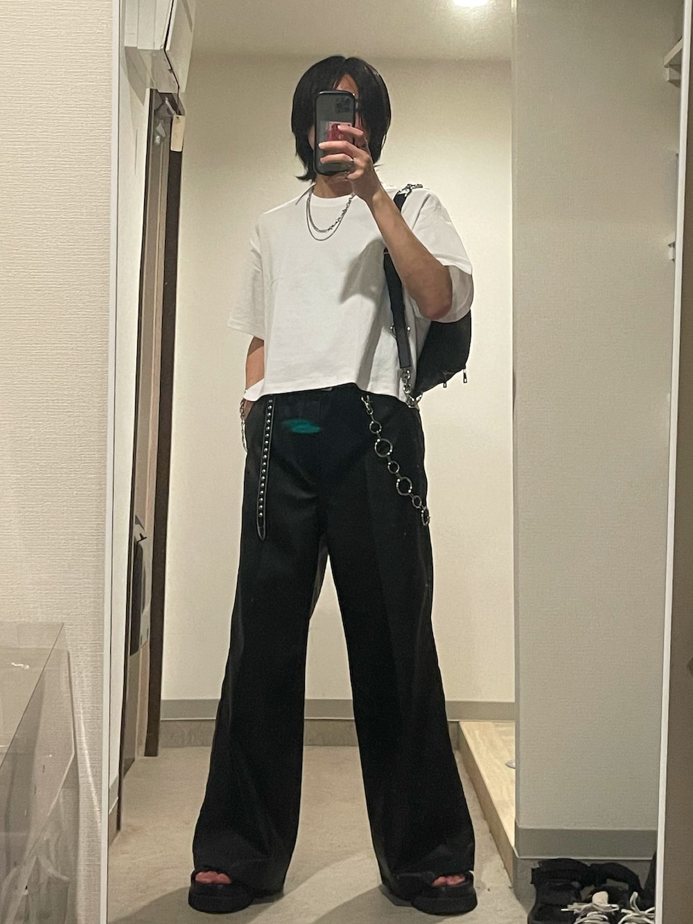 ブラック系のスラックス、ブラック系のショルダーバッグ、ブラック系のサンダルを着用したメンズの春コーディネートの2枚目の写真