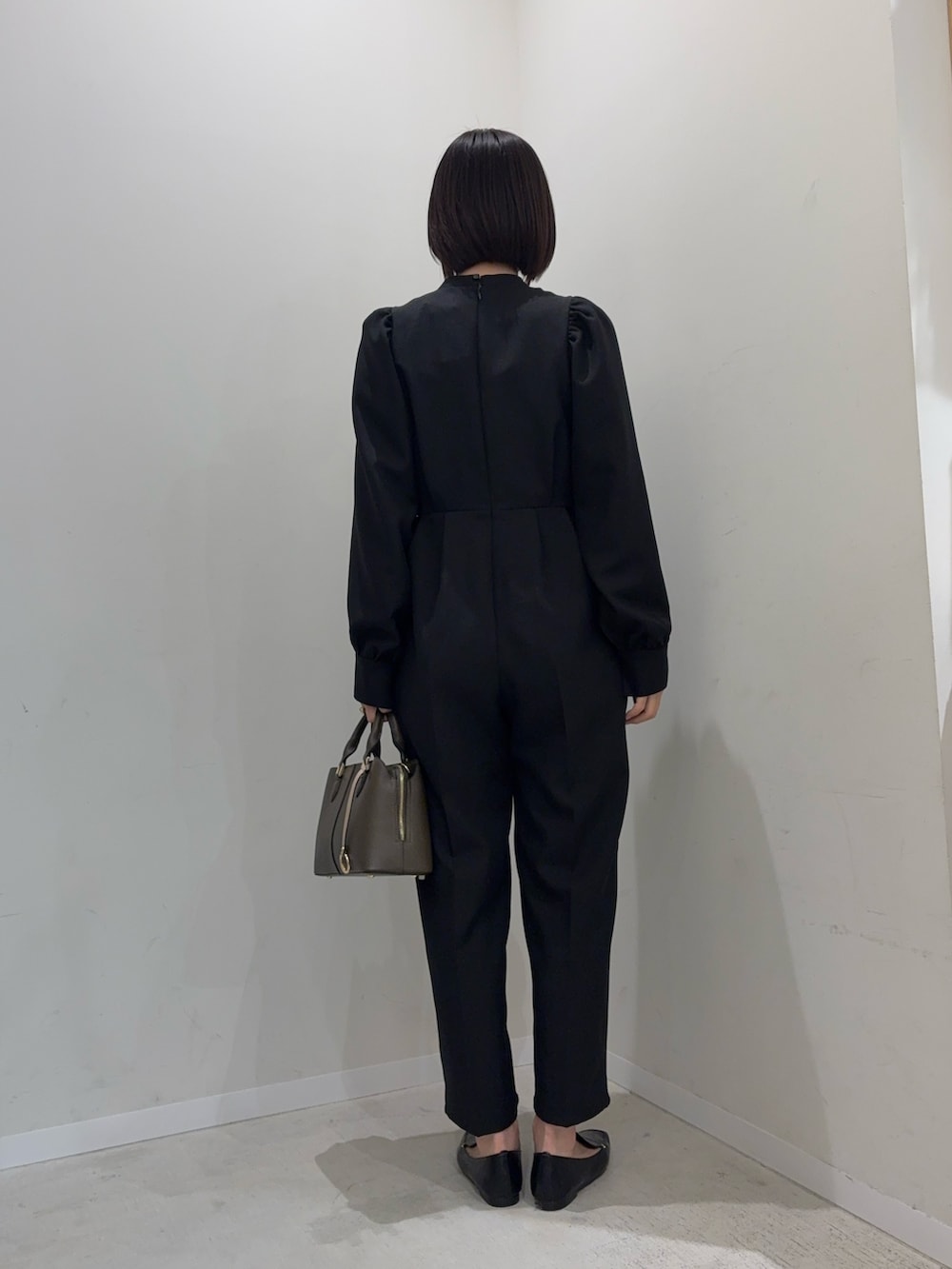 ブラック系のつなぎ/オールインワン、ベージュ系のハンドバッグを着用したレディースの冬コーディネートの2枚目の写真