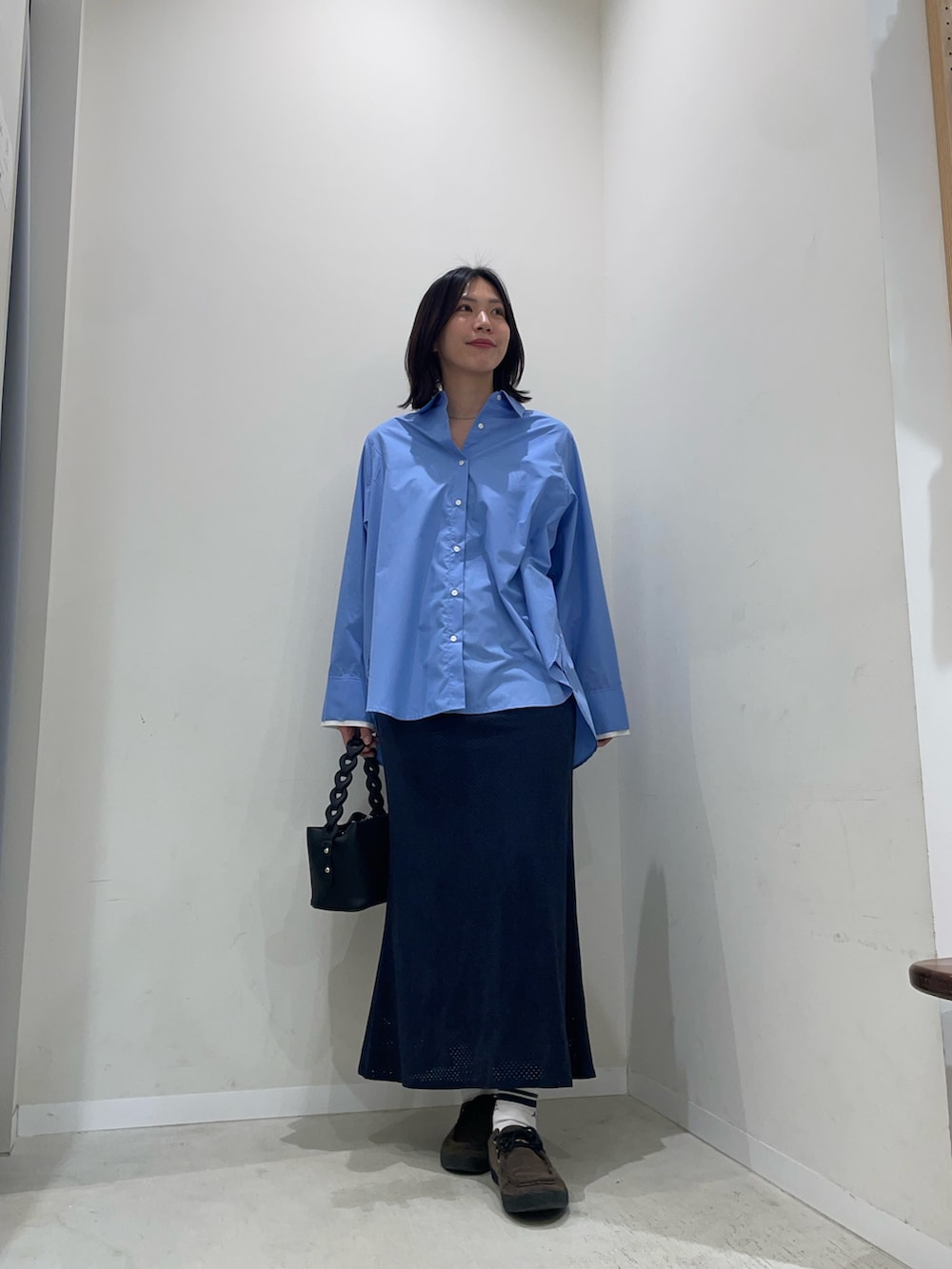 ブルー系のシャツ/ブラウス、ブルー系のスカート、ブラック系のショルダーバッグを着用したレディースの冬コーディネートの2枚目の写真