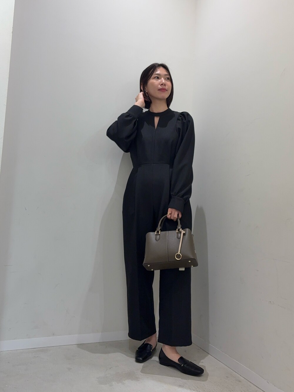ブラック系のつなぎ/オールインワン、ベージュ系のハンドバッグを着用したレディースの冬コーディネートの3枚目の写真
