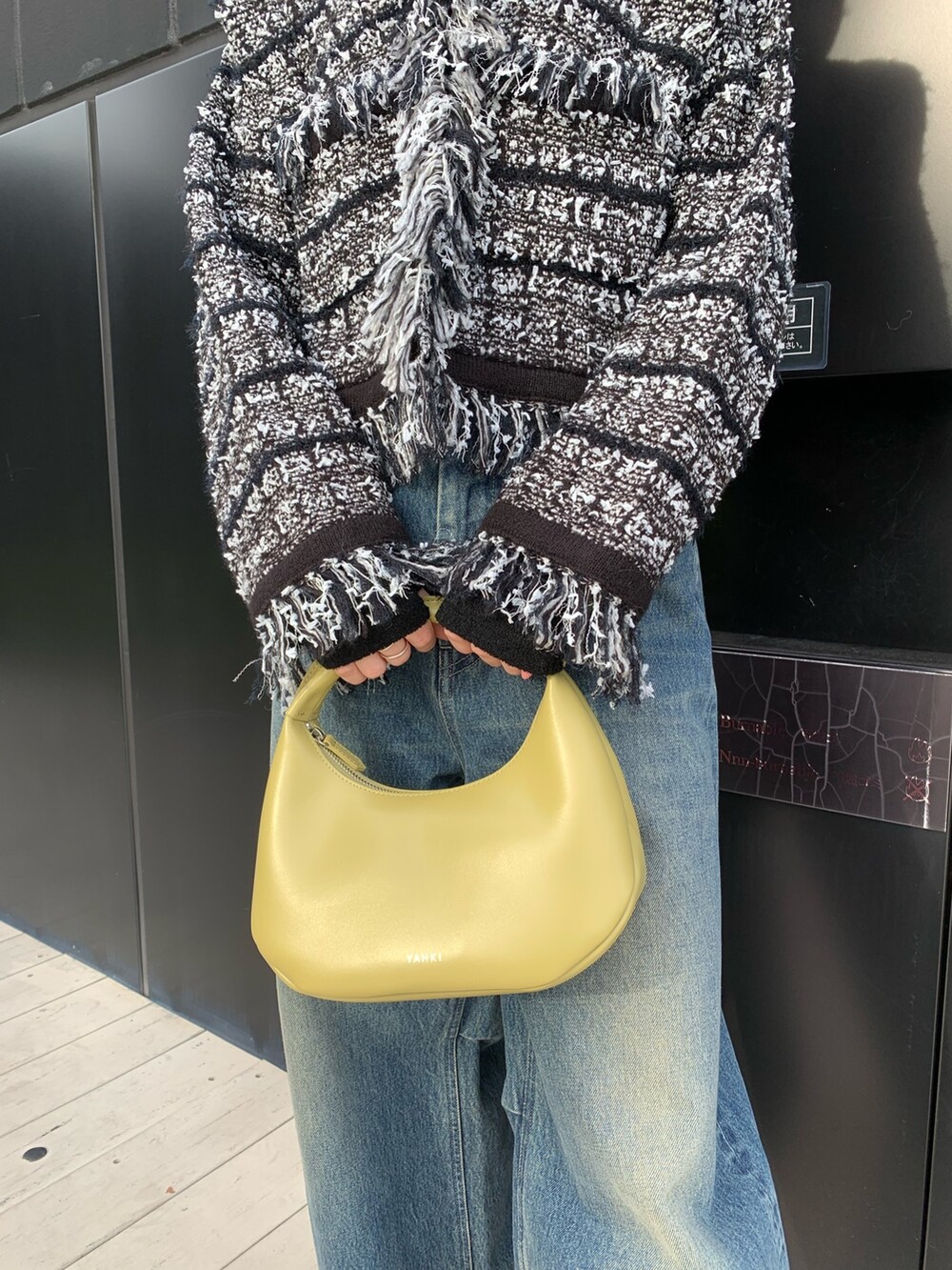ブルー系のデニムパンツ、シルバー系のブーツ、イエロー系のハンドバッグを着用したレディースの秋コーディネートの5枚目の写真