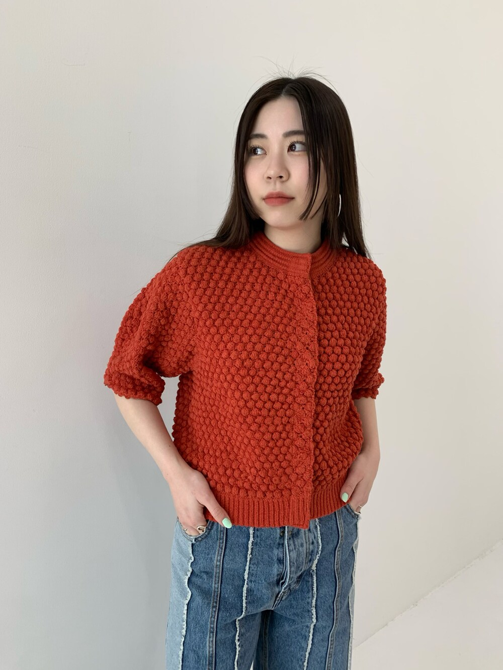 レッド系のカーディガン/ボレロ、ホワイト系のパンプス、ブルー系のデニムパンツを着用したレディースの春コーディネートの2枚目の写真
