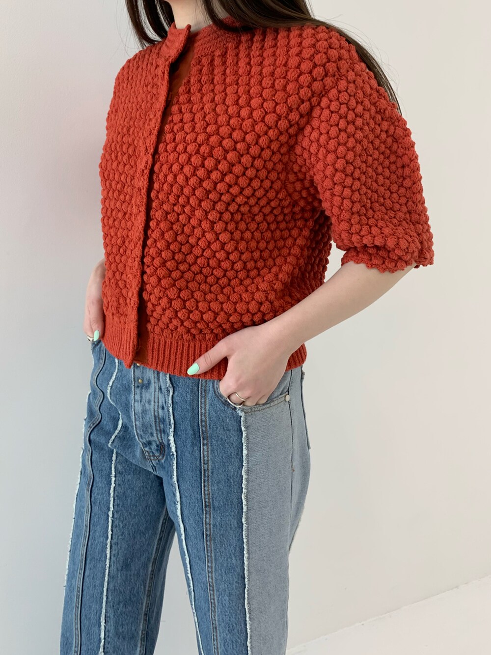 レッド系のカーディガン/ボレロ、ホワイト系のパンプス、ブルー系のデニムパンツを着用したレディースの春コーディネートの3枚目の写真
