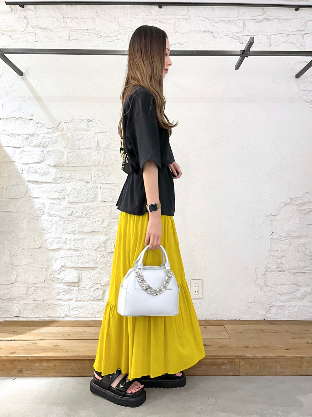 ブラック系のTシャツ/カットソー、イエロー系のスカート、シルバー系のショルダーバッグを着用したレディースの夏コーディネートの3枚目の写真