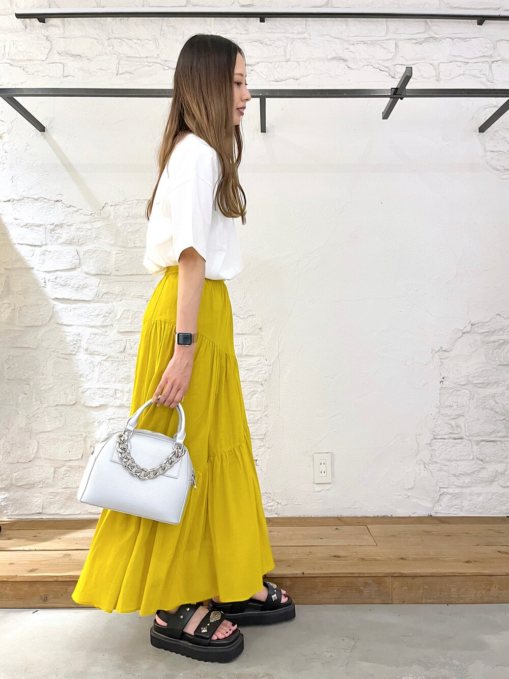 ホワイト系のTシャツ/カットソー、イエロー系のスカート、シルバー系のショルダーバッグを着用したレディースの夏コーディネートの2枚目の写真