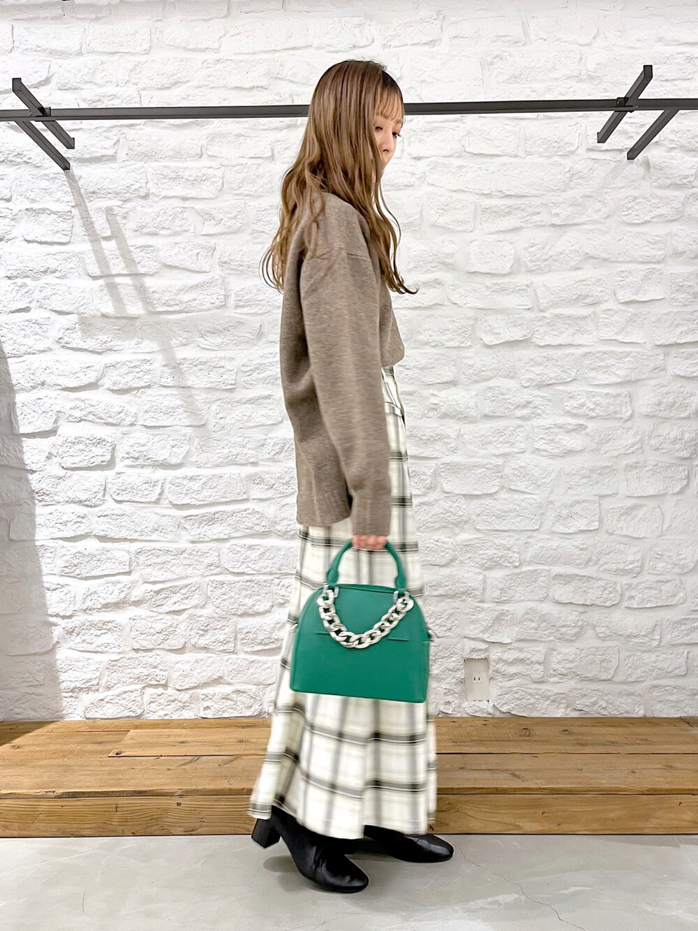 ブラウン系のニット/セーター、ホワイト系のスカート、ブラック系のブーツを着用したレディースの冬コーディネートの3枚目の写真