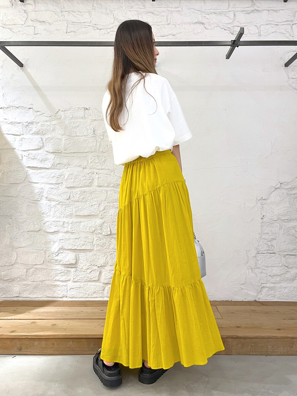 ホワイト系のTシャツ/カットソー、イエロー系のスカート、シルバー系のショルダーバッグを着用したレディースの夏コーディネートの3枚目の写真