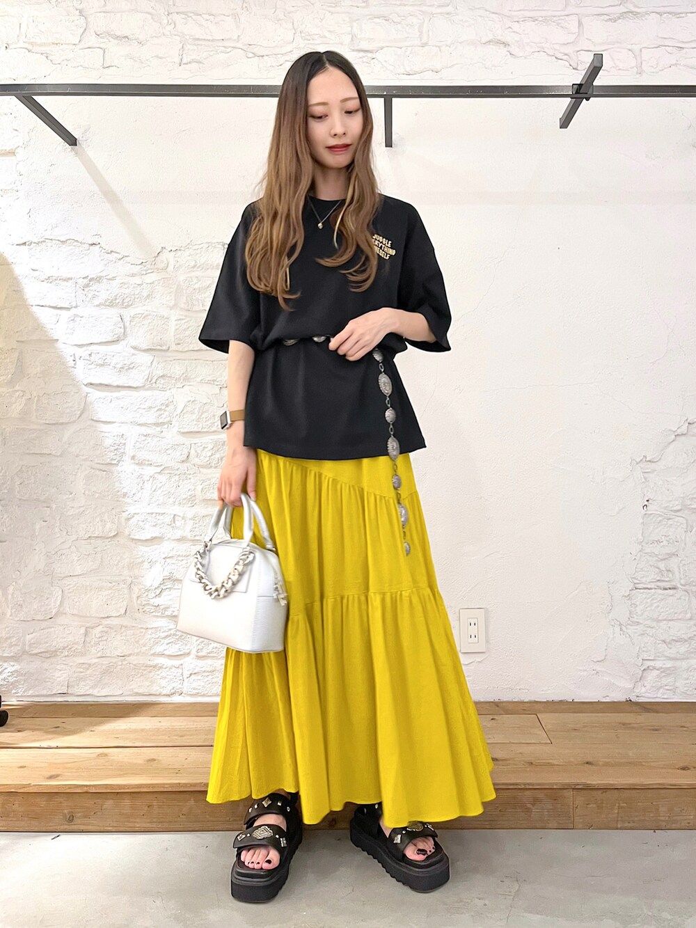 ブラック系のTシャツ/カットソー、イエロー系のスカート、シルバー系のショルダーバッグを着用したレディースの夏コーディネートの2枚目の写真