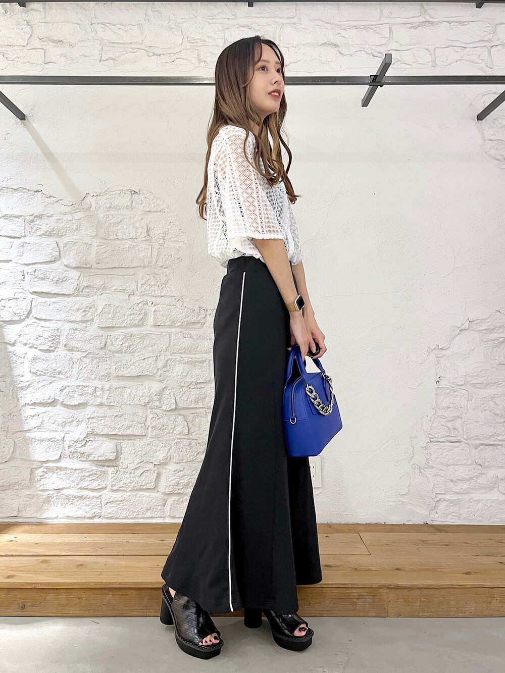 ホワイト系のシャツ/ブラウス、ブラック系のスカート、ブルー系のショルダーバッグを着用したレディースの夏コーディネートの2枚目の写真