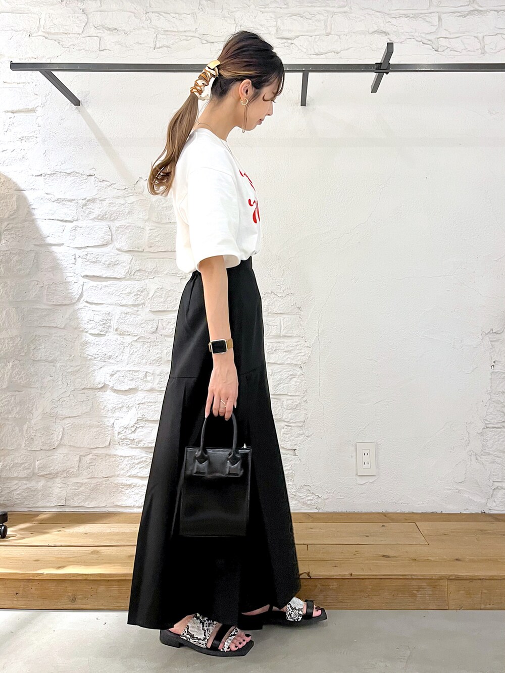 ホワイト系のTシャツ/カットソー、ブラック系のスカート、ブラック系のショルダーバッグを着用したレディースの夏コーディネートの2枚目の写真