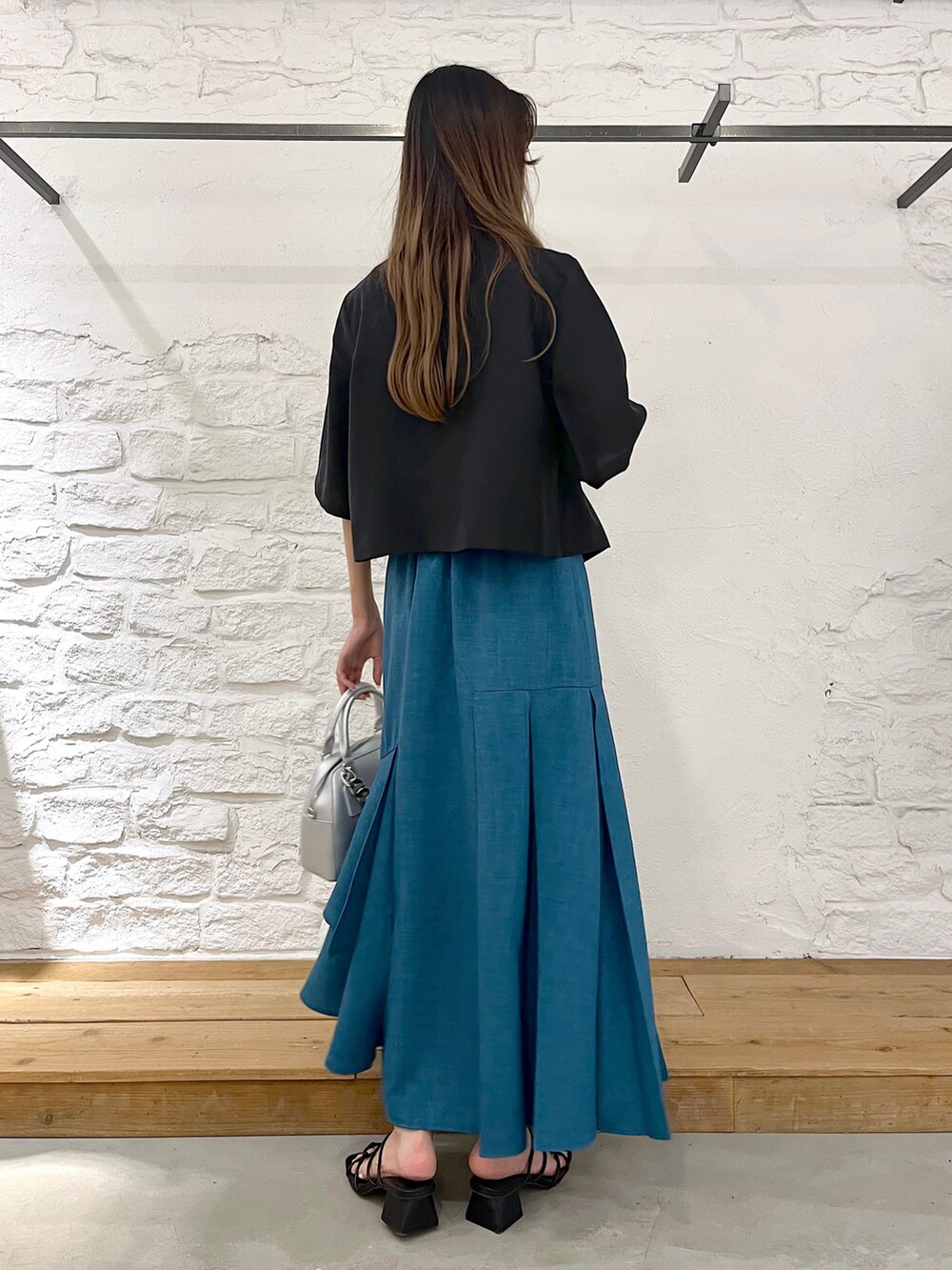 ブラック系のテーラードジャケット、ホワイト系のタンクトップ、ブルー系のスカートを着用したレディースの夏コーディネートの3枚目の写真